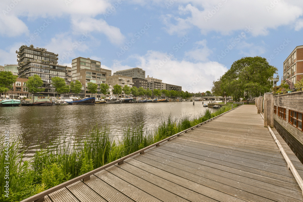 a dock with boats docked in the water and buildings on either side of the river, as seen from across the waterway a dock with boats docked in the water and buildings on either side of the river, as seen from across the waterway