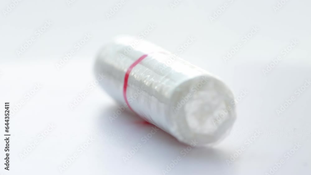White female tampon rotates on a white background, macro. The concept of hygiene in women during menstruation, gynecology White female tampon rotates on a white background, macro. The concept of hygiene in women during menstruation, gynecology
