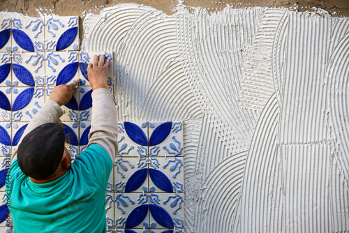 A builder, tiler placing 3 dimension azulejos on adhesive cement, exterior wall, Lagos, Algarve, Portugal, Europe