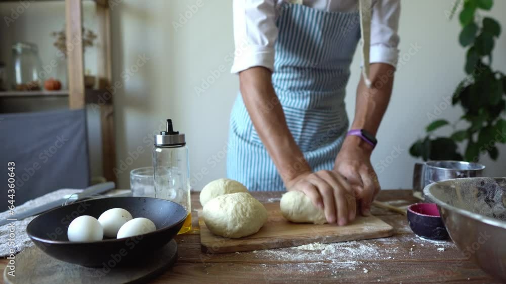 A baker in an apron kneads the dough with his hands and sprinkles it with flour to bake delicious homemade tortillas A baker in an apron kneads the dough with his hands and sprinkles it with flour to bake delicious homemade tortillas