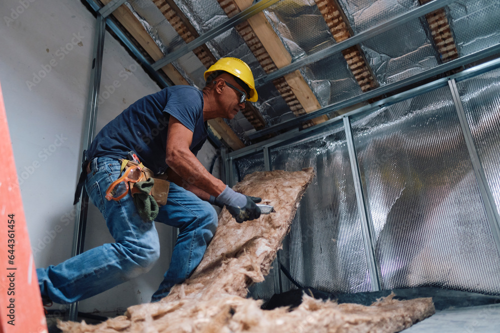 Mature construction worker working with insulation in attic Mature construction worker working with insulation in attic