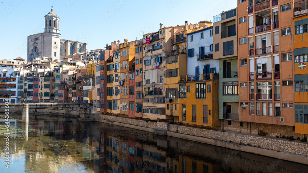 Pintoresque and colourfoul houses by the river with the church in the back in Girona