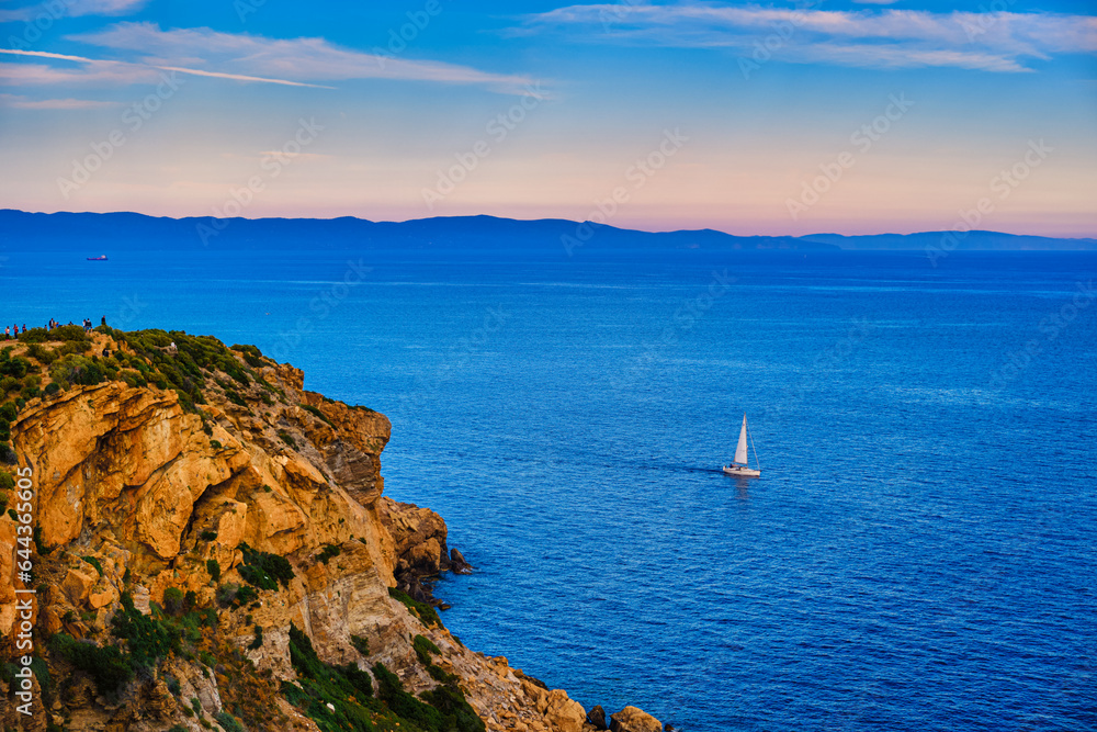 Sailboat navigating in Aegean sea near cape Sounion on sunset, Greece