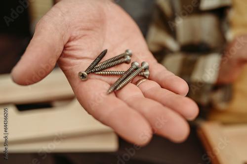 Hand of man holding metal screws