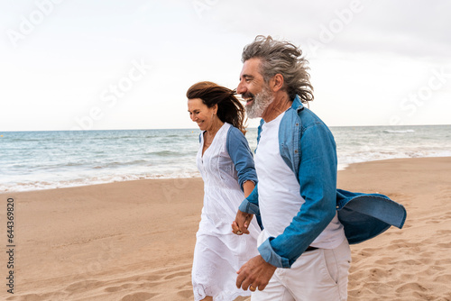 Happy senior couple enjoy walking on sand by sea