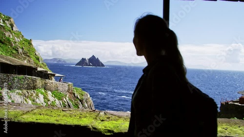 Silhouette of a young woman walking by ocean cliffside photo
