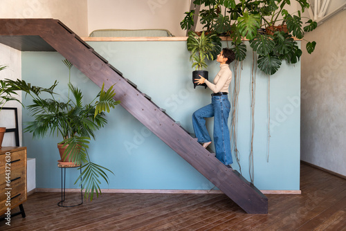 Woman holding plant and moving up on staircase