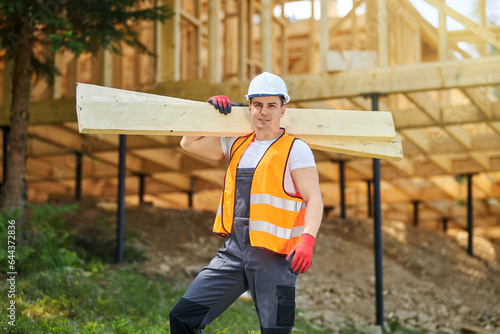 Konstfotografi Front view of man, worker wearing uniform and helmet, standing, holding wooden boards, gilders
