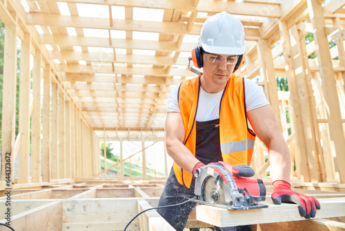 Photography Front view of craftsman, builder standing, looking down, cutting wodden gilder by professional equipment