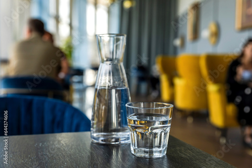 Glass of water and carafe on wooden table in cafe  atmosphere of a coffee shop in bokeh background