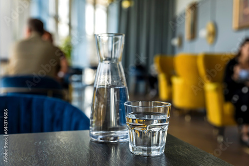 фотографія Glass of water and carafe on wooden table in cafe, atmosphere of a coffee shop i