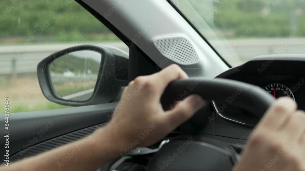 Close-up of musk hands on the steering wheel of a car, a trip out of town in the summer Close-up of musk hands on the steering wheel of a car, a trip out of town in the summer