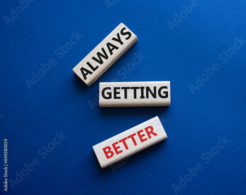 Always getting better symbol. Wooden blocks with words Always getting better. Beautiful deep blue background. Business and Always getting better concept. Copy space.