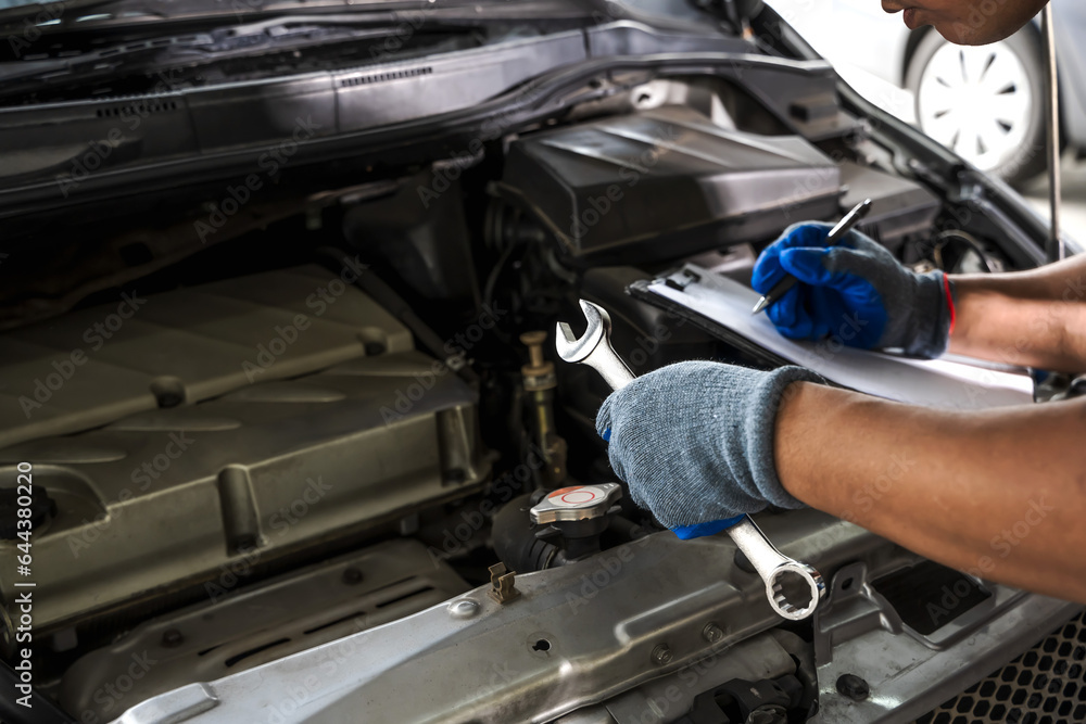 car mechanic holding wrench and doing check lists for car repairing car mechanic holding wrench and doing check lists for car repairing