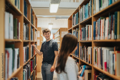 Happy students searching books on bookshelf in library at university photo