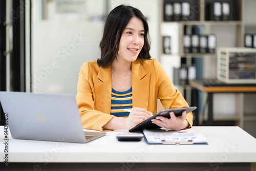 Business women hand working with tablet and laptop computer with documents on office desk in modern office.