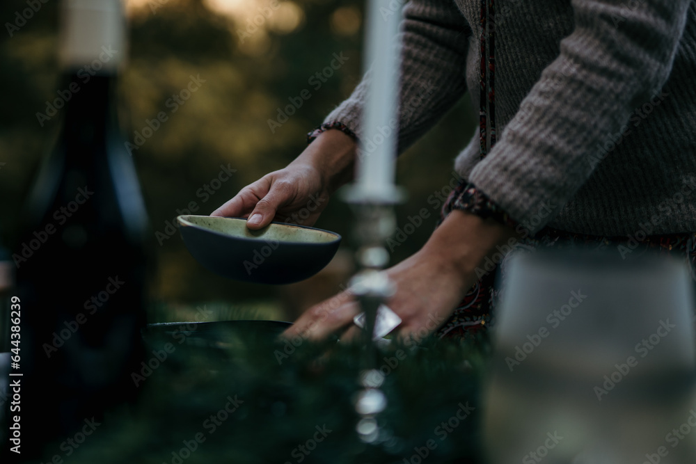 Woman setting up the table. The table is elegantly set with crisp white tablecloths, sparkling glassware, and polished silverware Woman setting up the table. The table is elegantly set with crisp white tablecloths, sparkling glassware, and polished silverware
