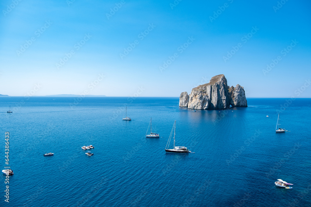 Boats off the coast of the crystal clear sea and rocks. Porto Flavia, Sardegna Italy
