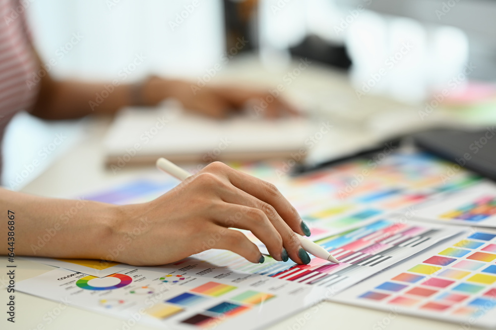 Creative woman using digital tablet and working with choosing color samples on desk at graphic studio Creative woman using digital tablet and working with choosing color samples on desk at graphic studio