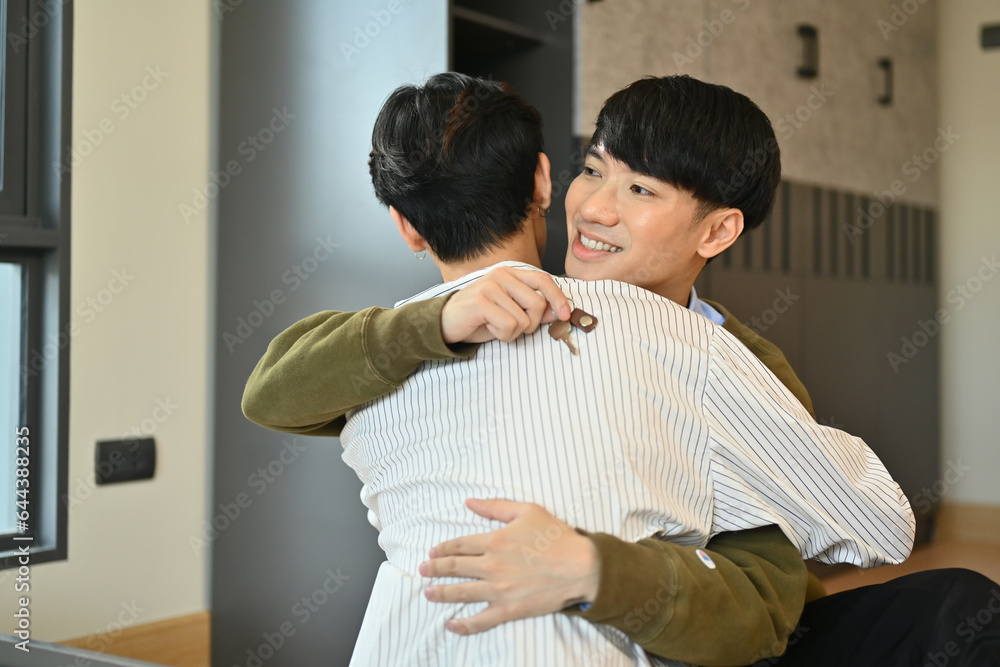Happy gay man couple celebrating moving into new home and hugging each other. LGBTQ, relocation and real estate property Happy gay man couple celebrating moving into new home and hugging each other. LGBTQ, relocation and real estate property