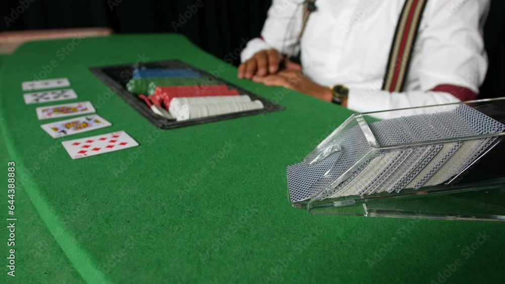 Poker game dealer dealing the flop card from dispenser in a casino at a black jack table Poker game dealer dealing the flop card from dispenser in a casino at a black jack table