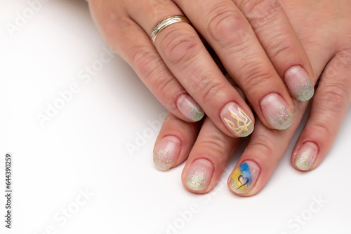 Patriotic manicure. Yellow-blue drawing and a heart. Shiny manicure on oval short nails with an offset to the right close-up