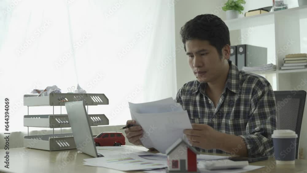 Planning and organizing household expenses (home, car, travel and credit cards) Young man calculating budget with tense and frustrated expression showing unhappy bills overdue car and house Planning and organizing household expenses (home, car, travel and credit cards) Young man calculating budget with tense and frustrated expression showing unhappy bills overdue car and house