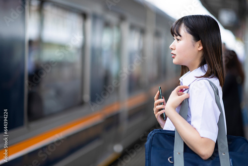 駅のホームに立つ女子高生