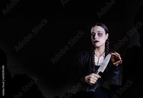 A woman with long braids  with gothic and dark look  plays with a butcher knife with her hand  in a spooky and spooky atmosphere  perfect for halloween