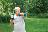 Senior man working out outdoors. Person lifting dumbbells. Old male exercising at park. Healthy people lifestyle. Active sport training. Older elderly sportsman doing fitness exercise. Workout session