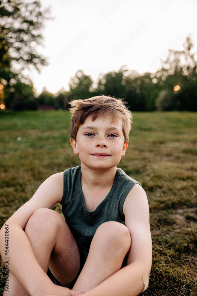 Portrait of boy sitting on grass in playground Portrait of boy sitting on grass in playground