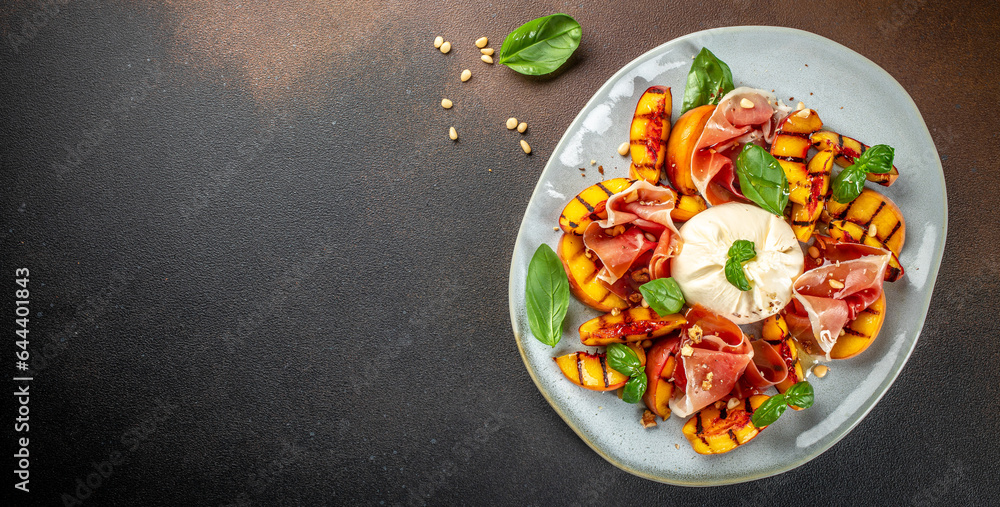 Grilled peach Caprese salad with mozzarella, prosciutto ham, basil and honey, for wine. Long banner format. top view