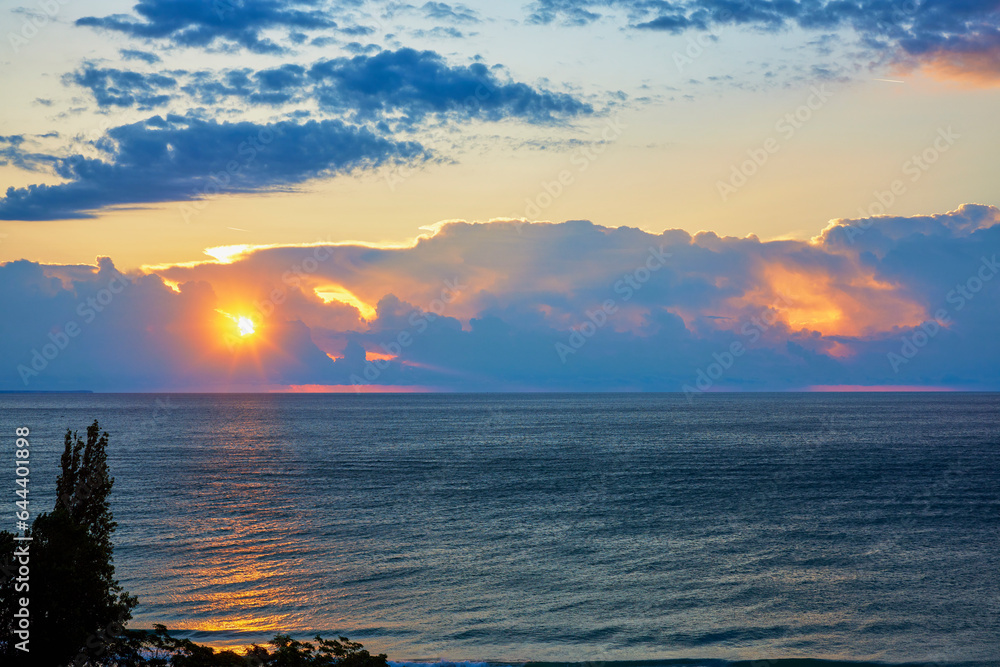 Landscape with the sunrise among the clouds at the sea.