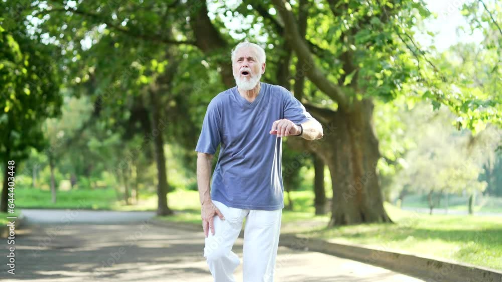 Senior gray haired man suffers from painful severe knee joint pain during a run in an city park. Mature old male massaging stretching trauma injury while jogging outdoors. Leg muscle cramp calf sport Senior gray haired man suffers from painful severe knee joint pain during a run in an city park. Mature old male massaging stretching trauma injury while jogging outdoors. Leg muscle cramp calf sport