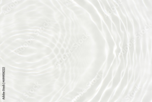 White water with ripples on the surface. Defocus blurred transparent white colored clear calm water surface texture with splashes and bubbles. Water waves with shining pattern texture background.