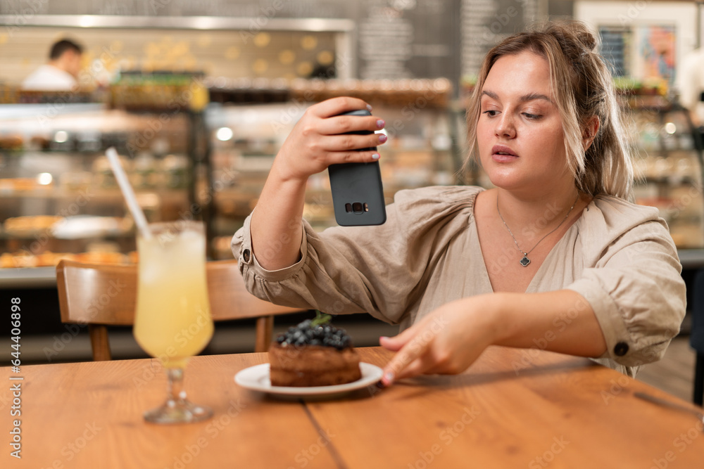 Young beautiful woman taking photo of dessert with smartphone for social media in restaurant