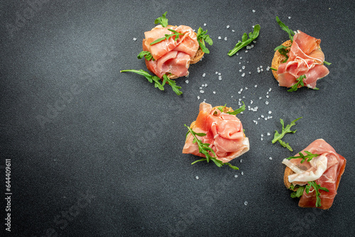 Fototapeta Naklejka Na Ścianę i Meble -  Spanish Tapas. jamon iberico ham, fresh toasts on a dark background, banner, menu, recipe place for text, top view