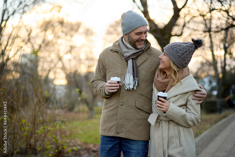 A happy romantic couple with coffee walking in the park