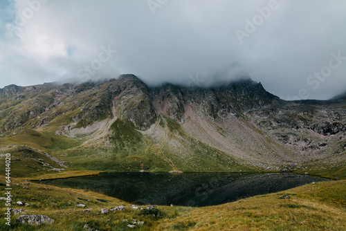 High mountain glacial lake. Mountains covered with clouds. Foggy landscape. Caucasus mountains © Tetiana