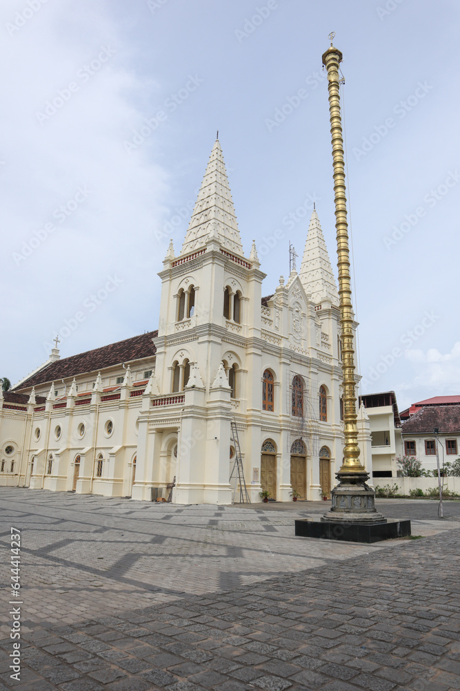 A Low angle picture of the Iconic 'Santa Cruz Cathedral Basilica' Church with the Brass Pillar or Manasthamba in front in Kochi city of Kerala state, India.