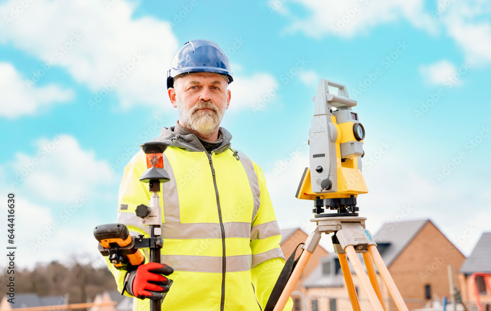 Surveyor builder site engineer with theodolite total station at construction site outdoors during surveying work Surveyor builder site engineer with theodolite total station at construction site outdoors during surveying work