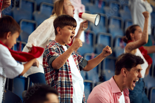 Young people and children attending live football match, loudly cheering up favourite team during game. Concept of sport, cup, world, team, event, competition, emotions, championship, betting