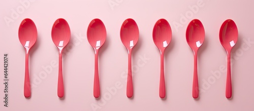 Set of red plastic measuring spoons for preparing milk or food on isolated pastel background Copy space