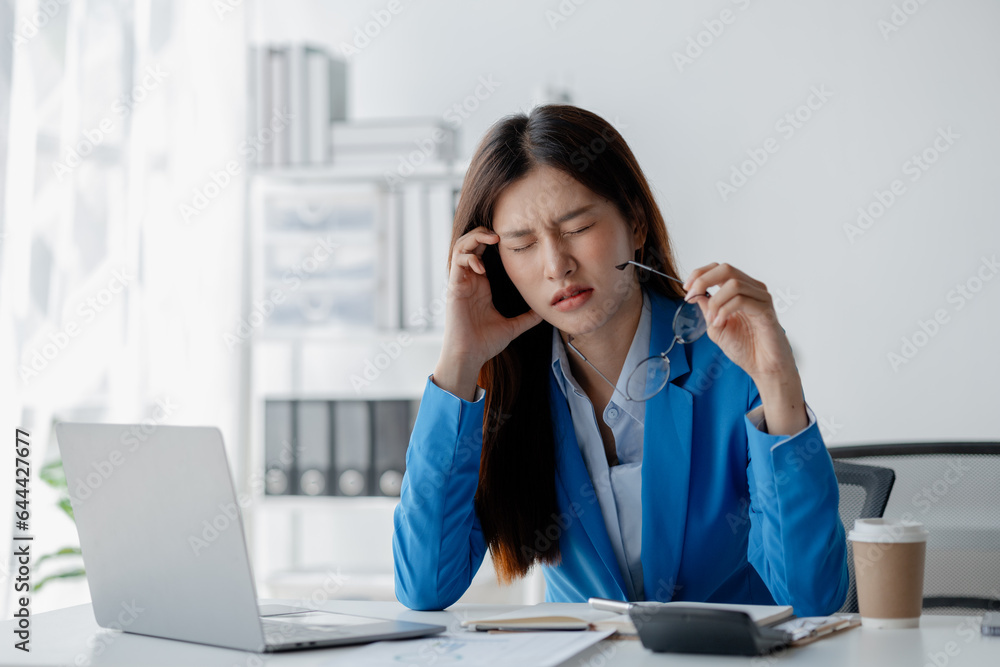 Asian woman in a startup company office, businesswoman poses stressed and body aches due to long hours of hard work, office syndrome among working people. Office syndrome concept and hard work. Asian woman in a startup company office, businesswoman poses stressed and body aches due to long hours of hard work, office syndrome among working people. Office syndrome concept and hard work.