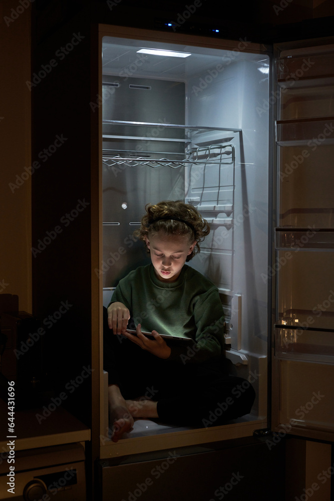 Boy sitting in fridge with tablet Boy sitting in fridge with tablet