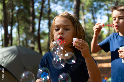 Two children blowing to make soap bubbles in the woods