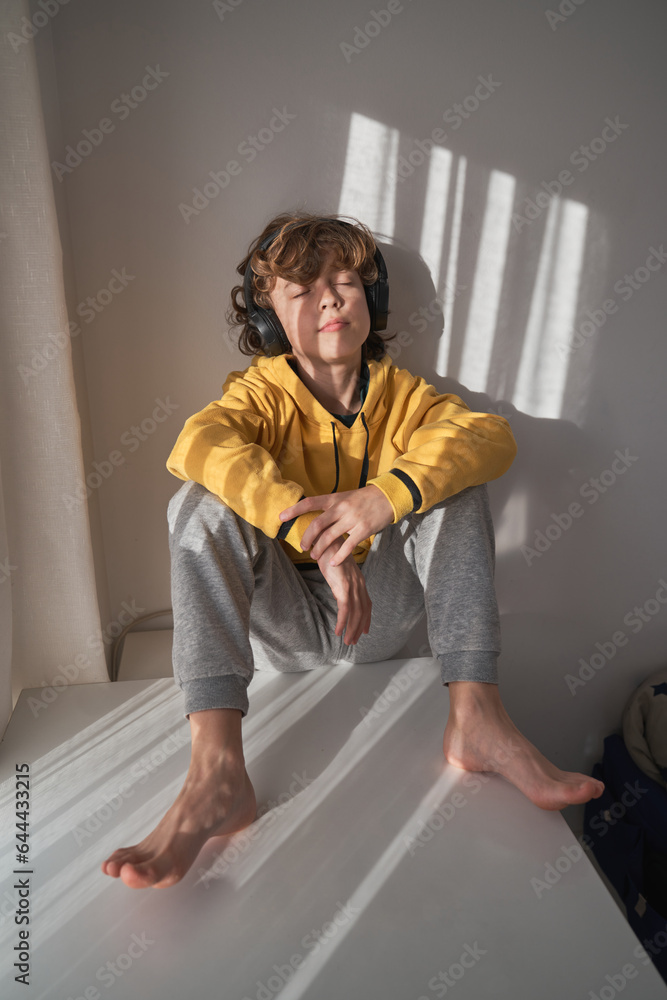 Boy in headphones sitting against wall Boy in headphones sitting against wall