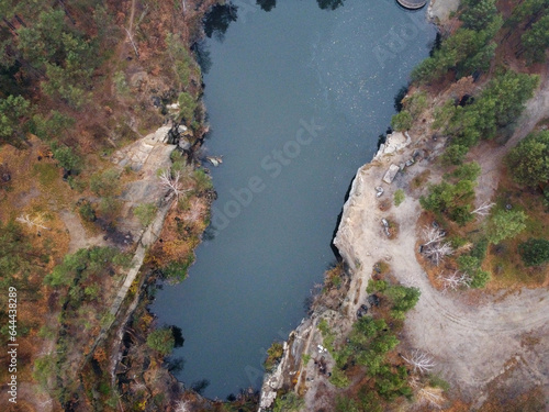 Picturesque aerial view of landscape with emerald lake and rocks in the middle of a coniferous autumn forest in Korostyshiv granite quarry  Zhytomyr district  northern Ukraine. Zhytomyr canyon