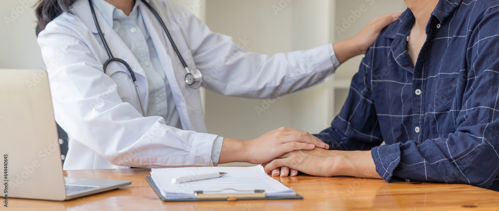 Female doctor giving encouragement to male patient by holding hand and a shoulder tap Female doctor giving encouragement to male patient by holding hand and a shoulder tap