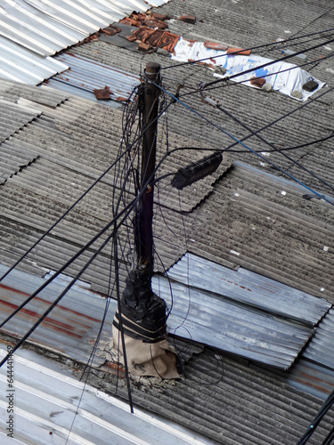 Wire tangled on the power poles, electric poles on the roof of the house with power lines scattered around. photo